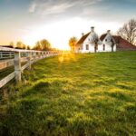 Beautiful shot of a fence leading to a house in a green grass area