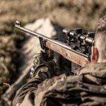 The man is on the hunt. Hunt hunting rifle. Hunter man. Hunter with hunting gun and hunting form to hunt. Hunter is aiming. Shooter sighting in the target