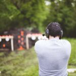 Shallow focus shot from behind of a male shooting a gun at a gun range