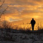 Winter hunting at sunrise. Hunter moving With Shotgun and Lookin